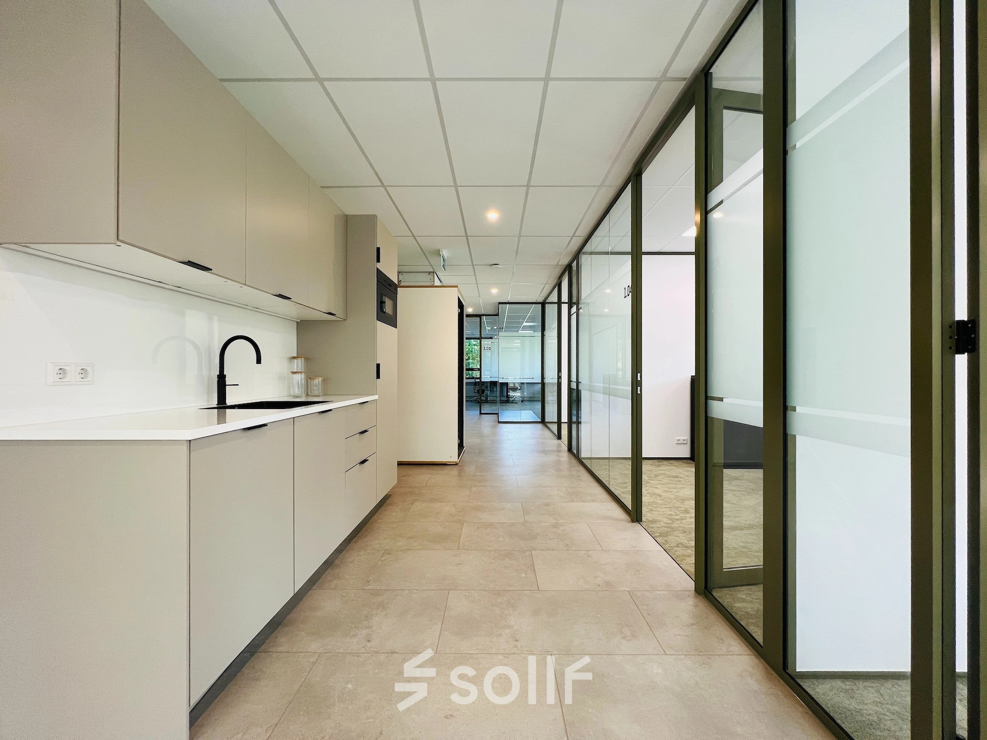 Modern office space rental at Marathon 2, Hilversum, featuring a sleek interior with glass partitions and cabinetry.
