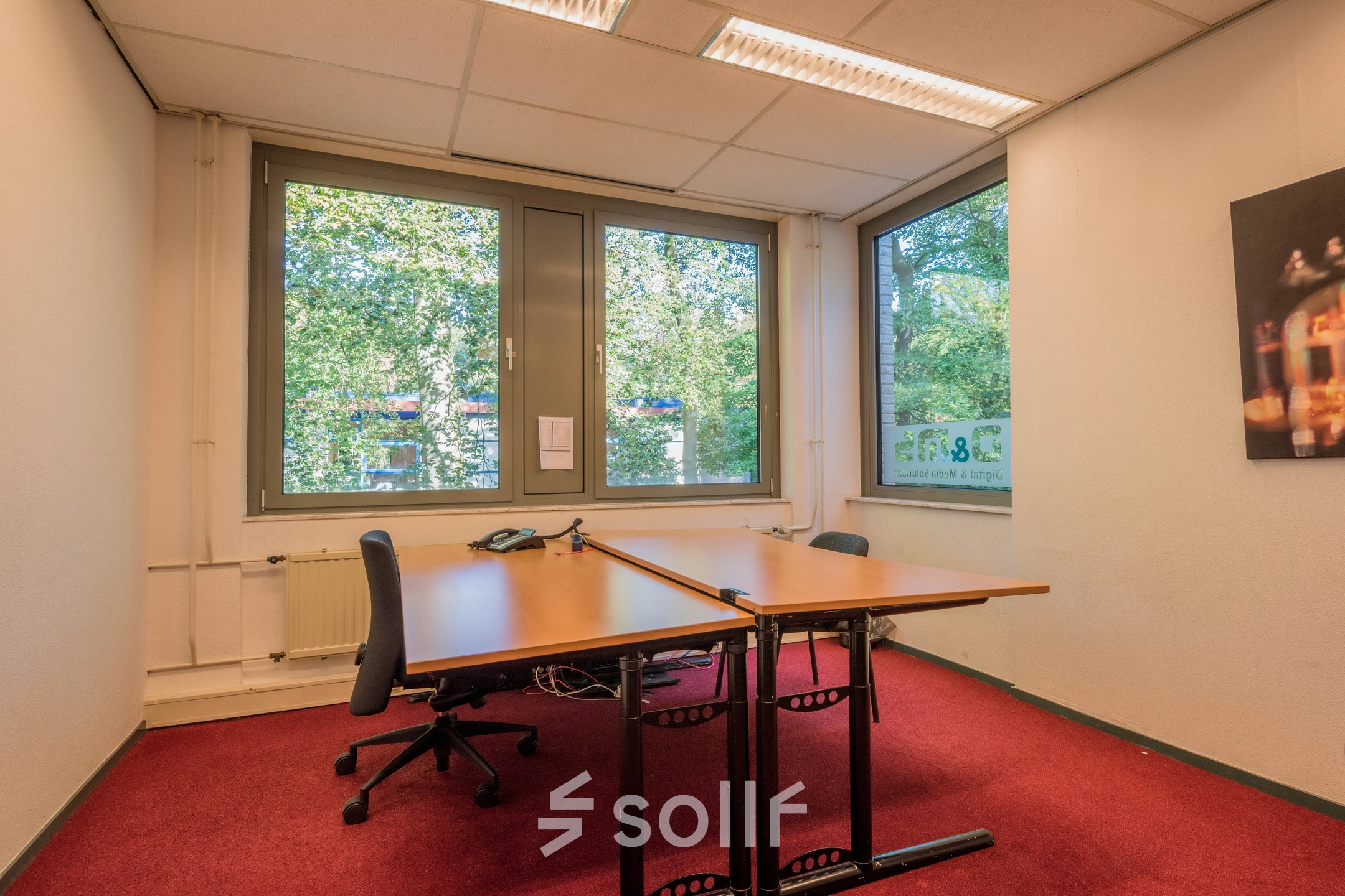 An office to rent in Hilversum featuring two desks and chairs, with large windows offering natural light. Ideal for office space rental at Mozartlaan 27.