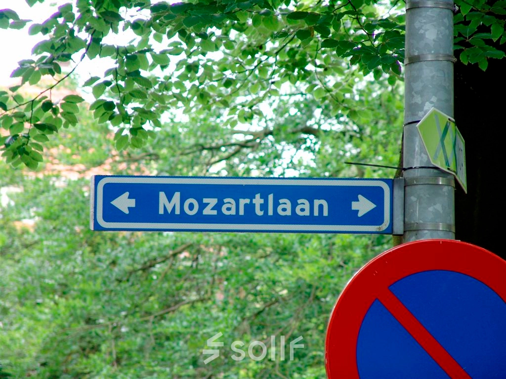 Street sign pointing to Mozartlaan in a leafy area of Hilversum.