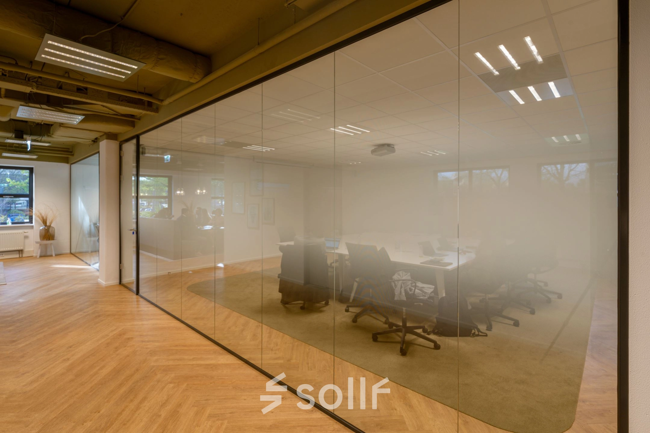 Spacious conference room at Olympia 1 in Hilversum with glass walls and modern furnishings, perfect for office space rental.