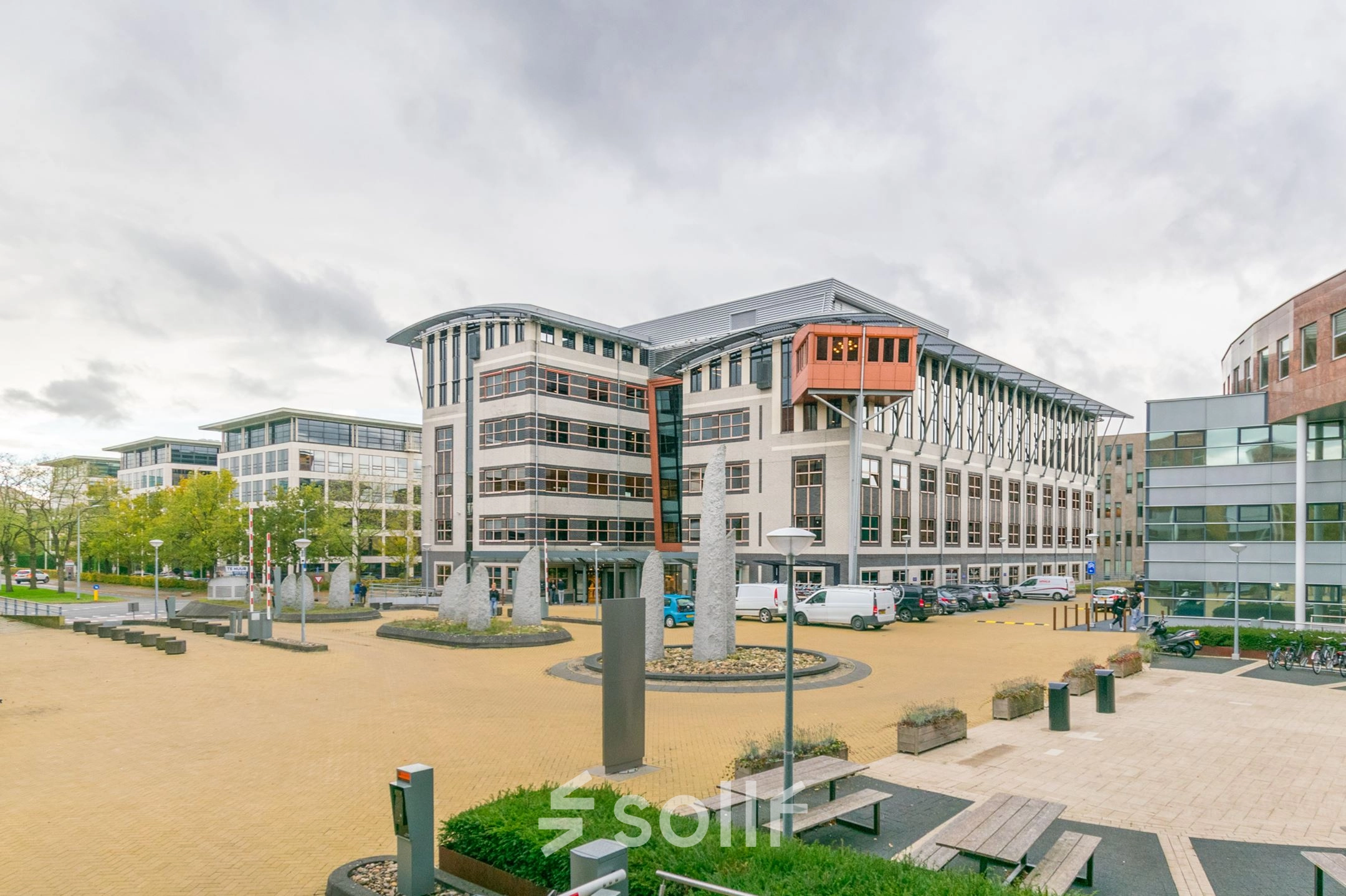 Exterior view of Olympia 1 in Hilversum with modern architecture, ideal for office space rental. Ample outdoor area provides a welcoming environment.