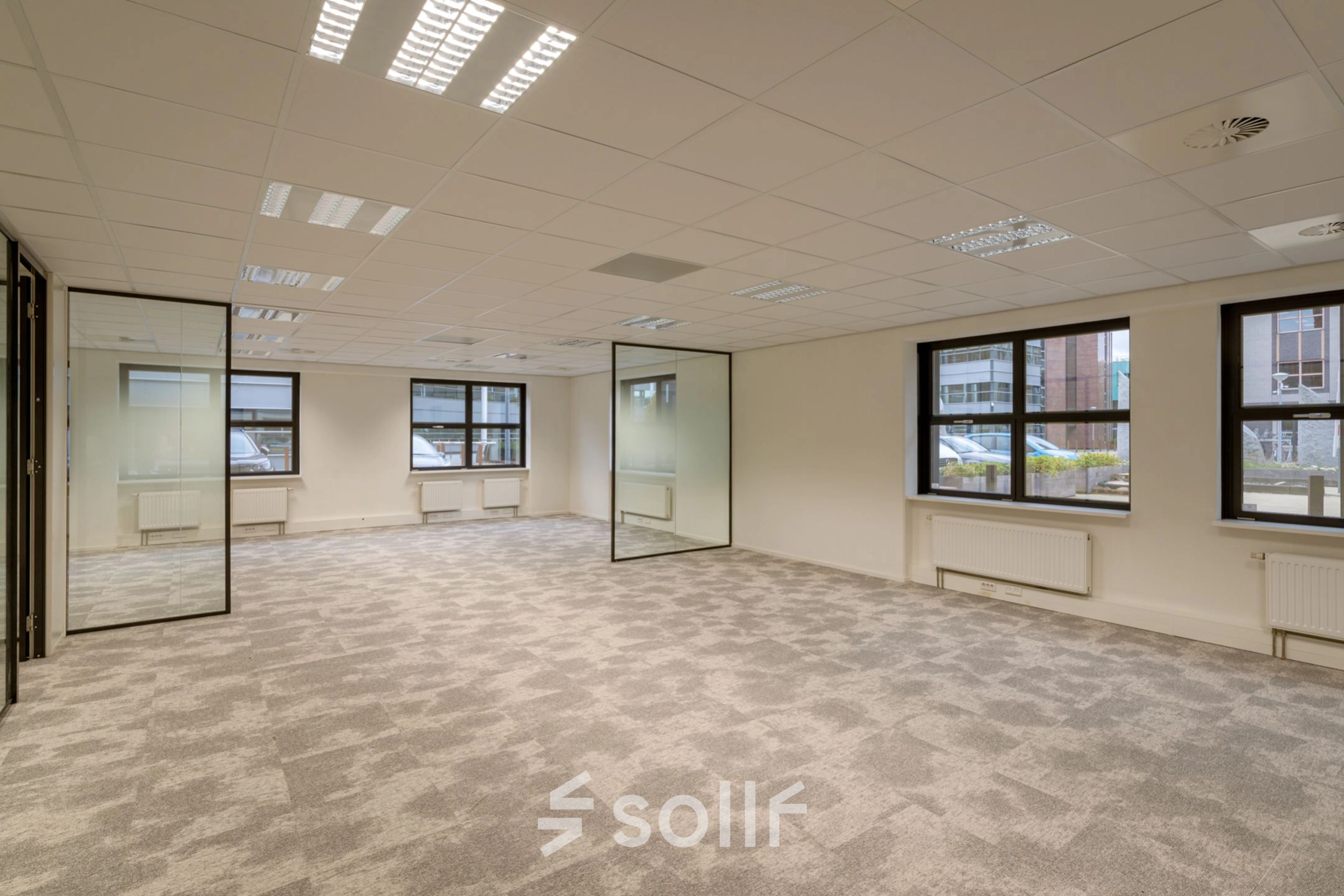 Spacious office space to rent at Olympia 1, Hilversum, featuring large windows and carpeted flooring.