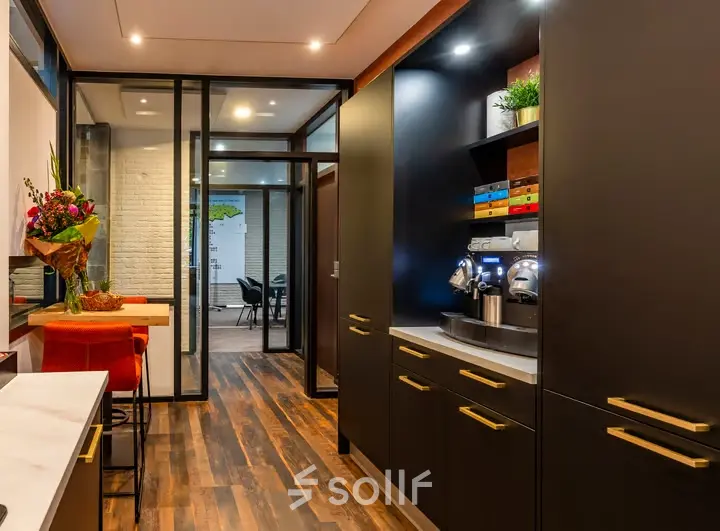 Furnished office space for rent at Steijnlaan 16, Hilversum, featuring sleek cabinetry and a coffee station, leading to a meeting area.