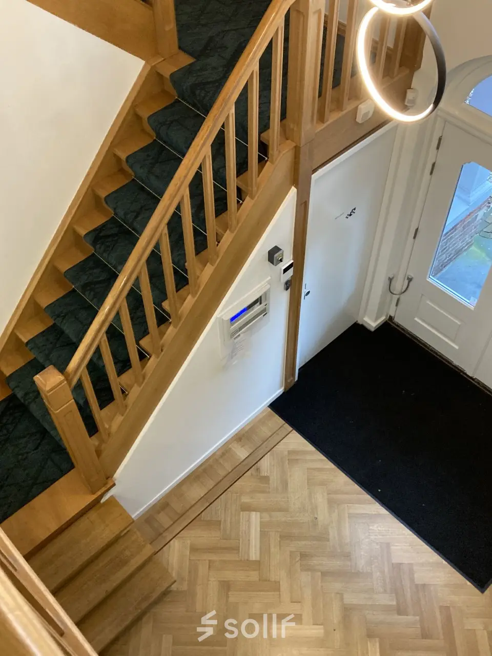 Interior view of office entryway at Utrechtseweg 47, Hilversum, featuring wooden stairs and parquet flooring, suitable for office space rental.