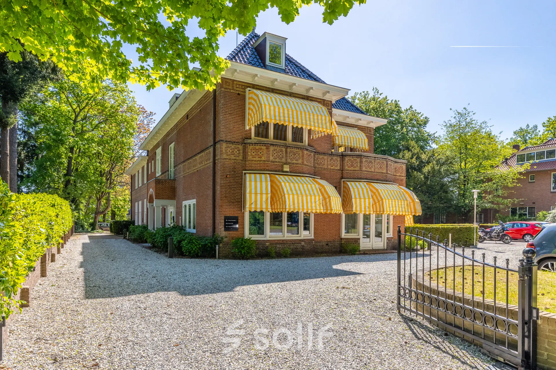 Exterior view of an office space rental at Utrechtseweg 47, Hilversum with a brick facade and striped awnings.