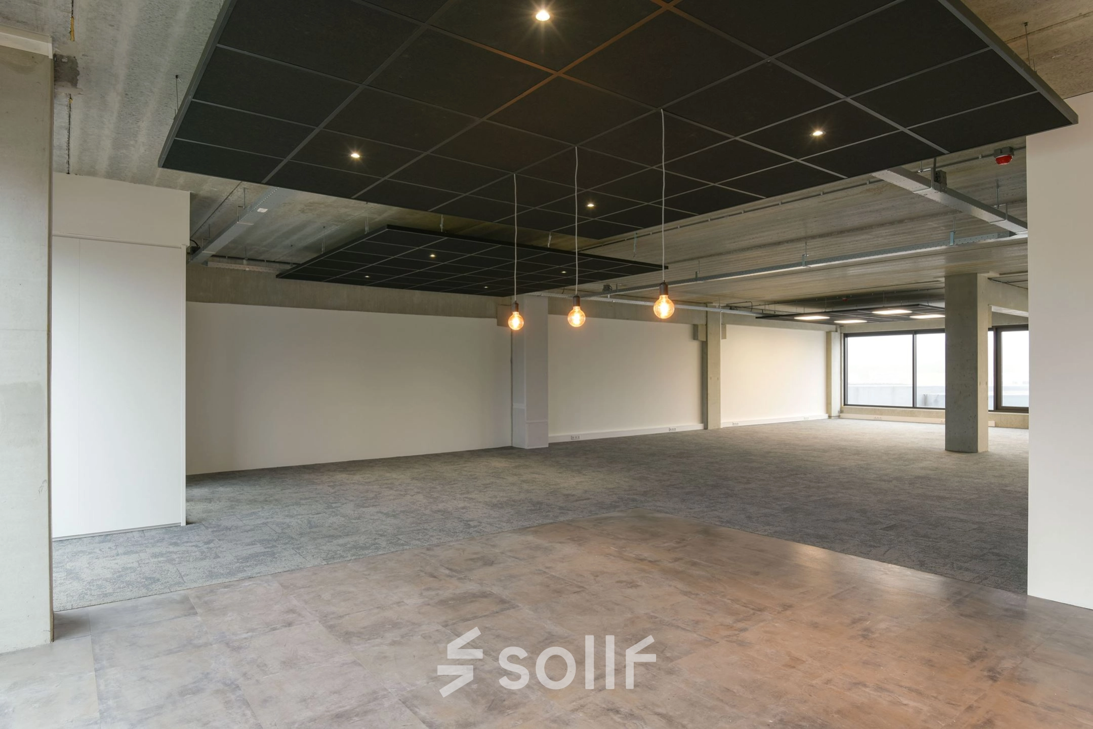 Wide open office space available for rent in Hilversum at Zuiderloswal 55, featuring large windows and modern lighting, ideal for customization.