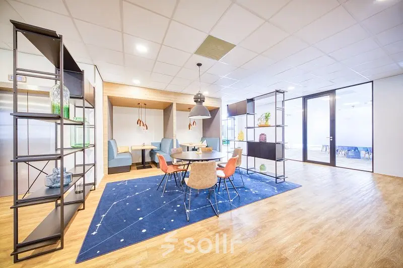 Bright office space for rent at Polarisavenue 130-150, Hoofddorp with modern furnishings including a round table, chairs, and decorative shelving, ideal for casual meetings.