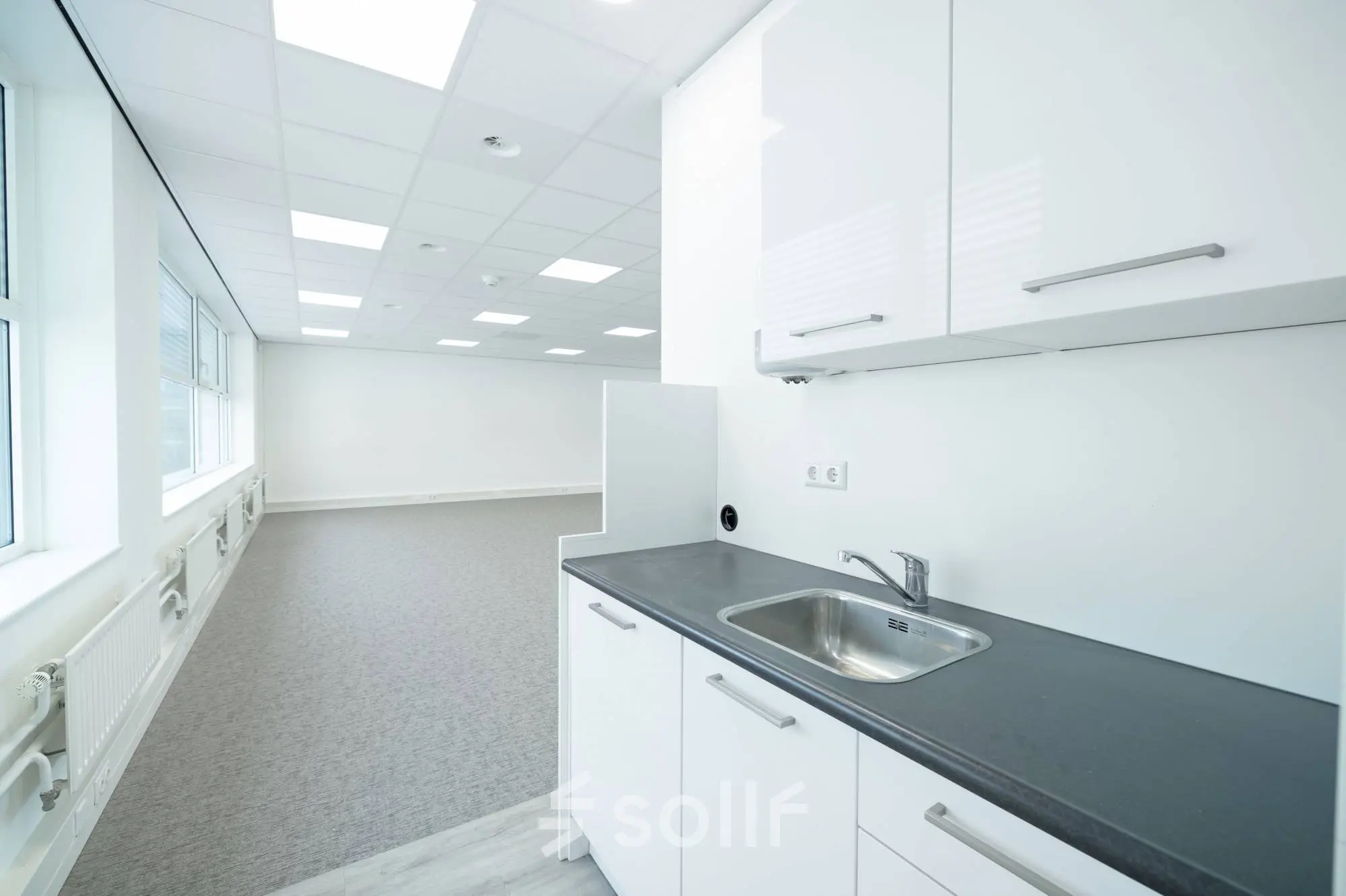 Bright office space rental at Polarisavenue 130-150, Hoofddorp, featuring a clean kitchenette and spacious open floor area with ample natural light.