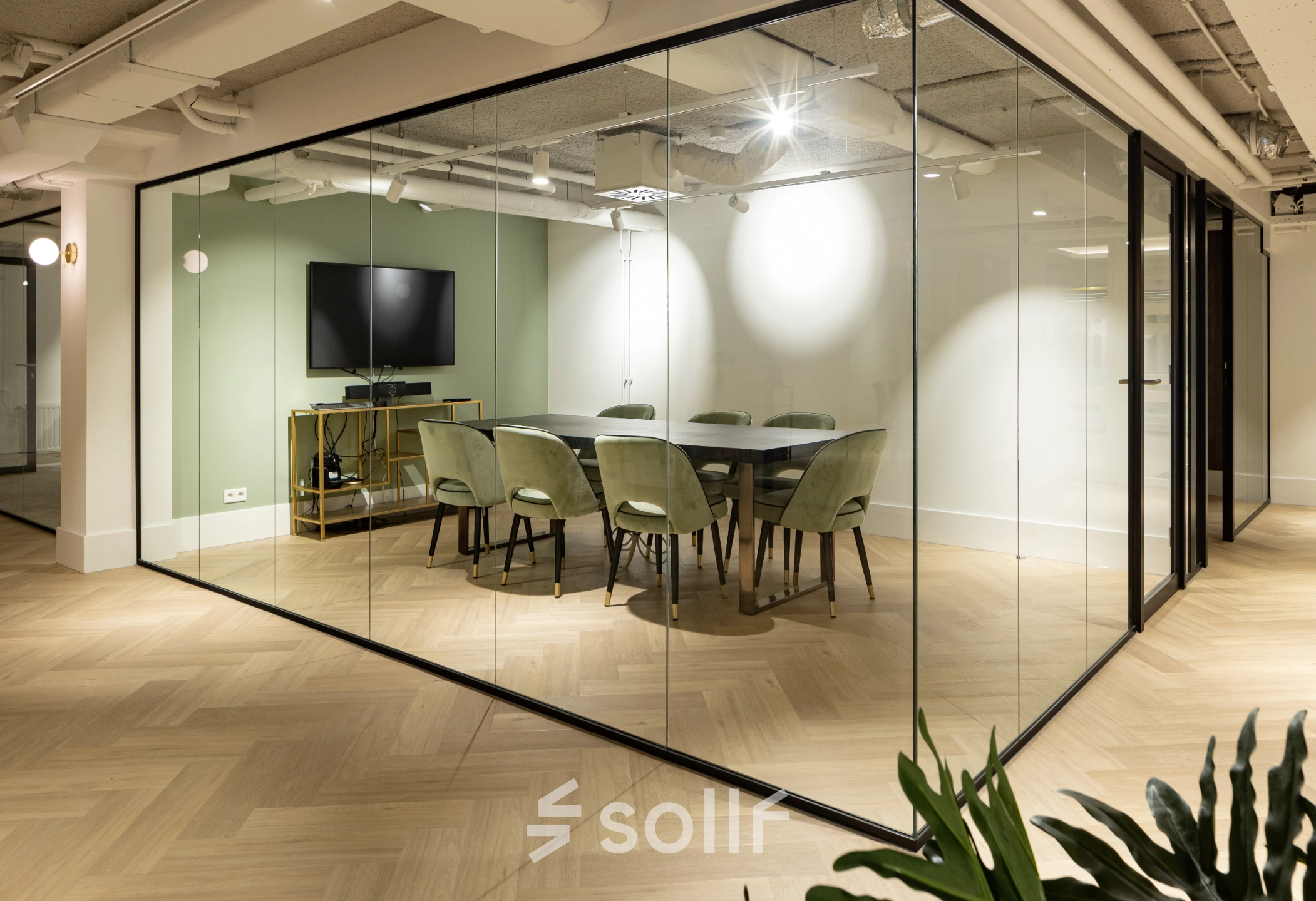 Modern conference room at Siriusdreef 60, Hoofddorp, featuring a large round table, green chairs, and a wall-mounted TV. Ideal office space rental for productive meetings.