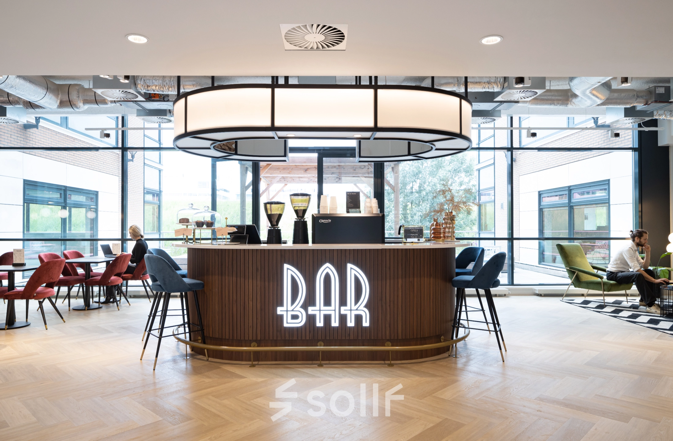 Spacious lounge area at Siriusdreef 60, Hoofddorp, featuring a modern bar with stylish seating and large windows. Ideal for office space rental with relaxed communal vibes.