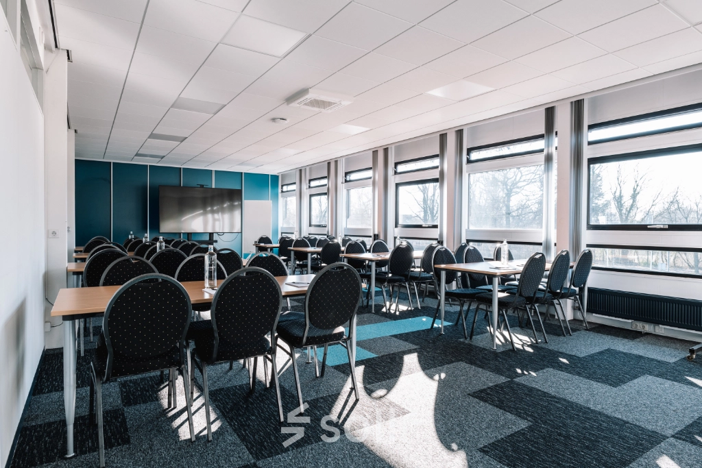 Bright office space rental at De Vos van Steenwijklaan 75 in Hoogeveen, featuring rows of chairs and tables ideal for meetings or conferences.