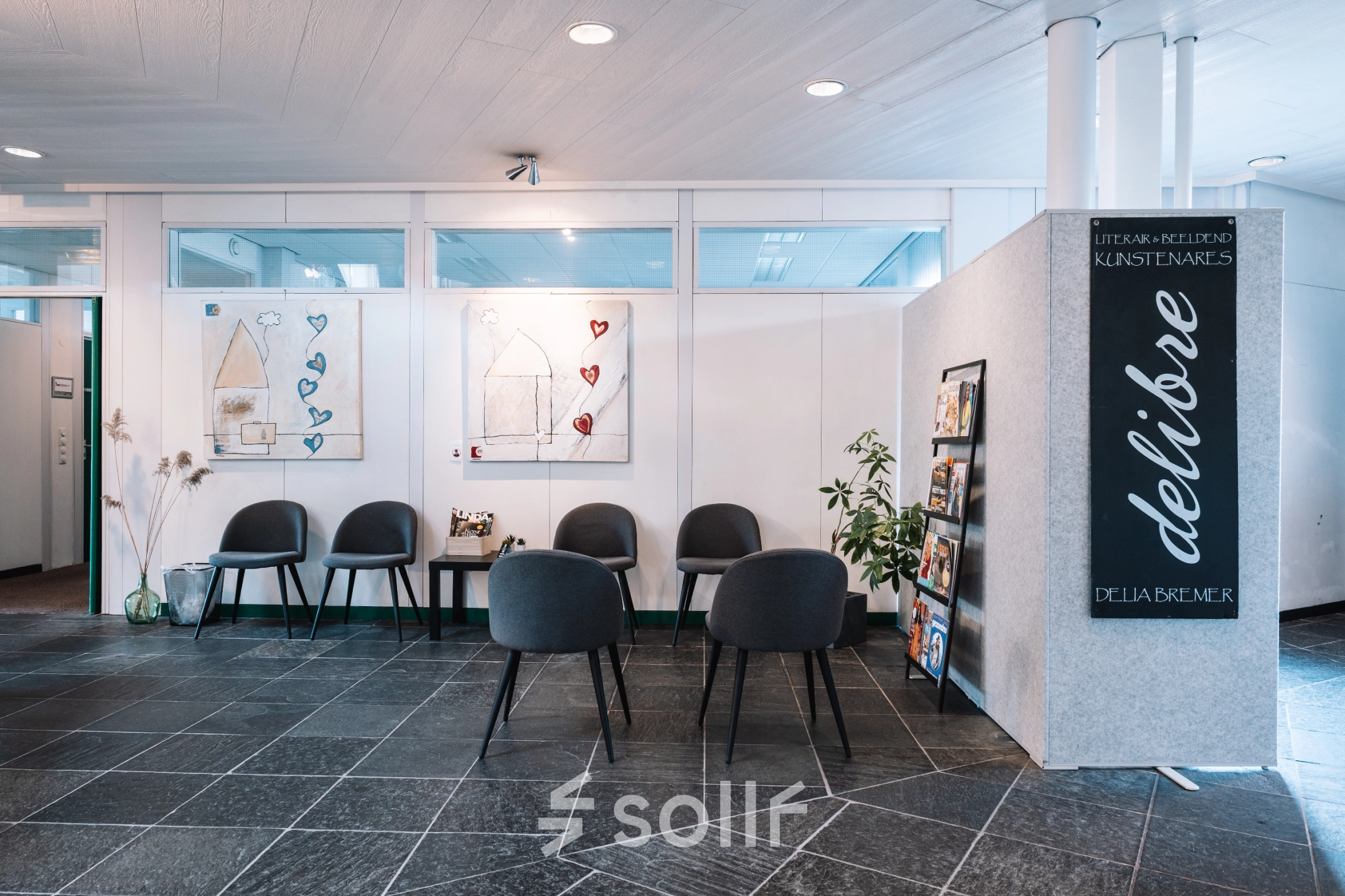 Reception area at De Vos van Steenwijklaan 75 in Hoogeveen, ideal for office space rental with a modern touch. Chairs and art adorn the space, inviting inquiries for an office to rent.