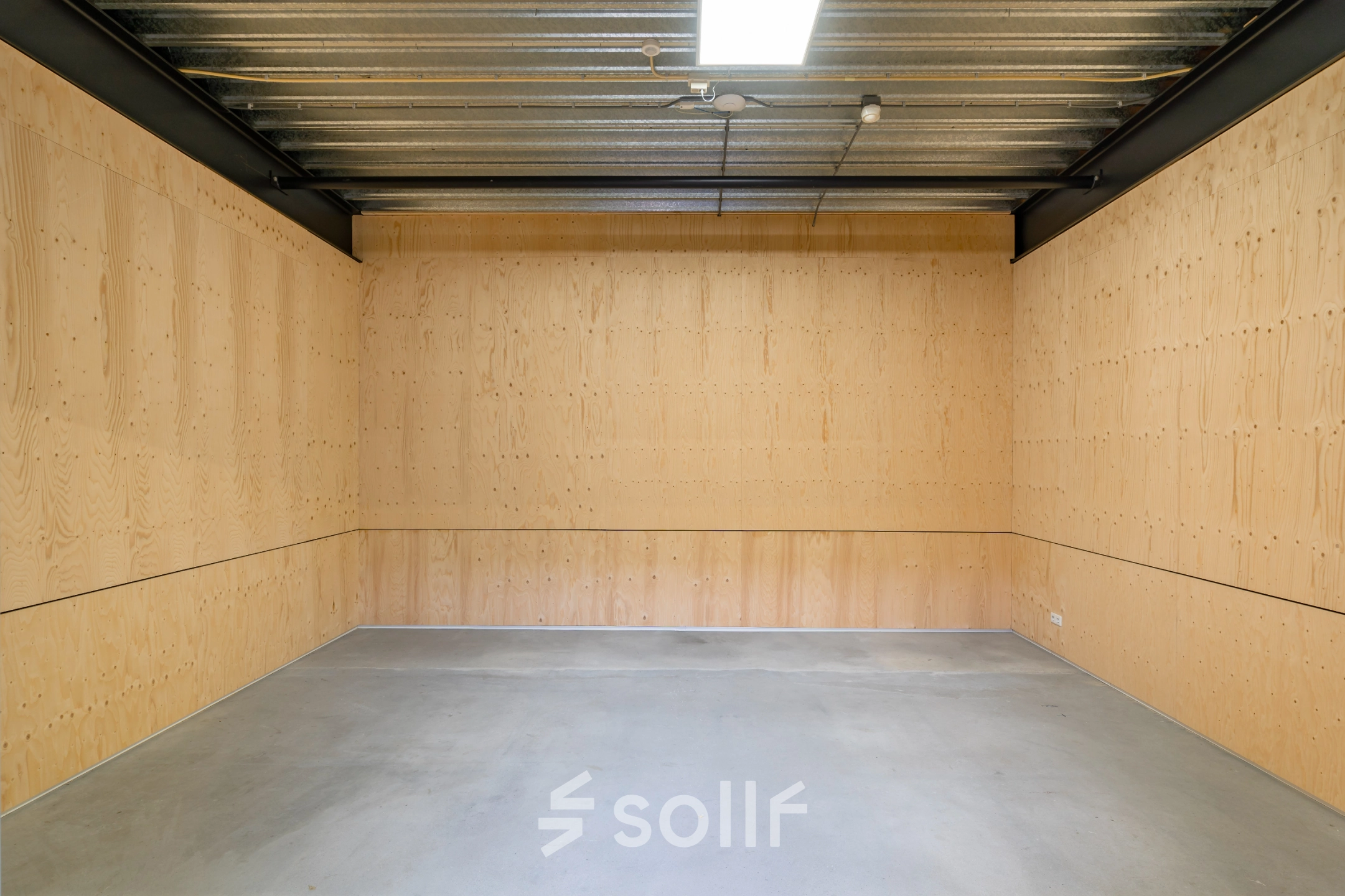 Simple interior space with light wooden walls and concrete flooring, perfect for office space rental at Hoofdveste 2, Houten.
