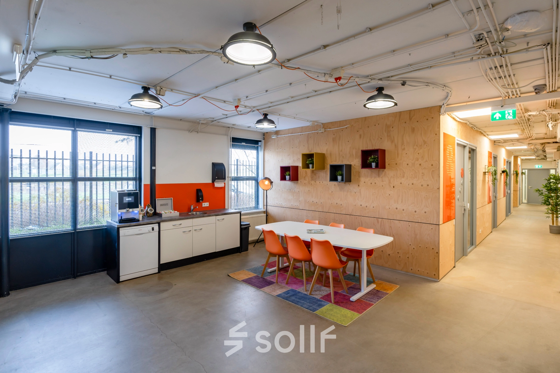 Modern office interior at Hoofdveste 2, Houten, featuring a bright multipurpose space with a meeting table and kitchenette. Ideal for office space rental in a vibrant, colorful setting.