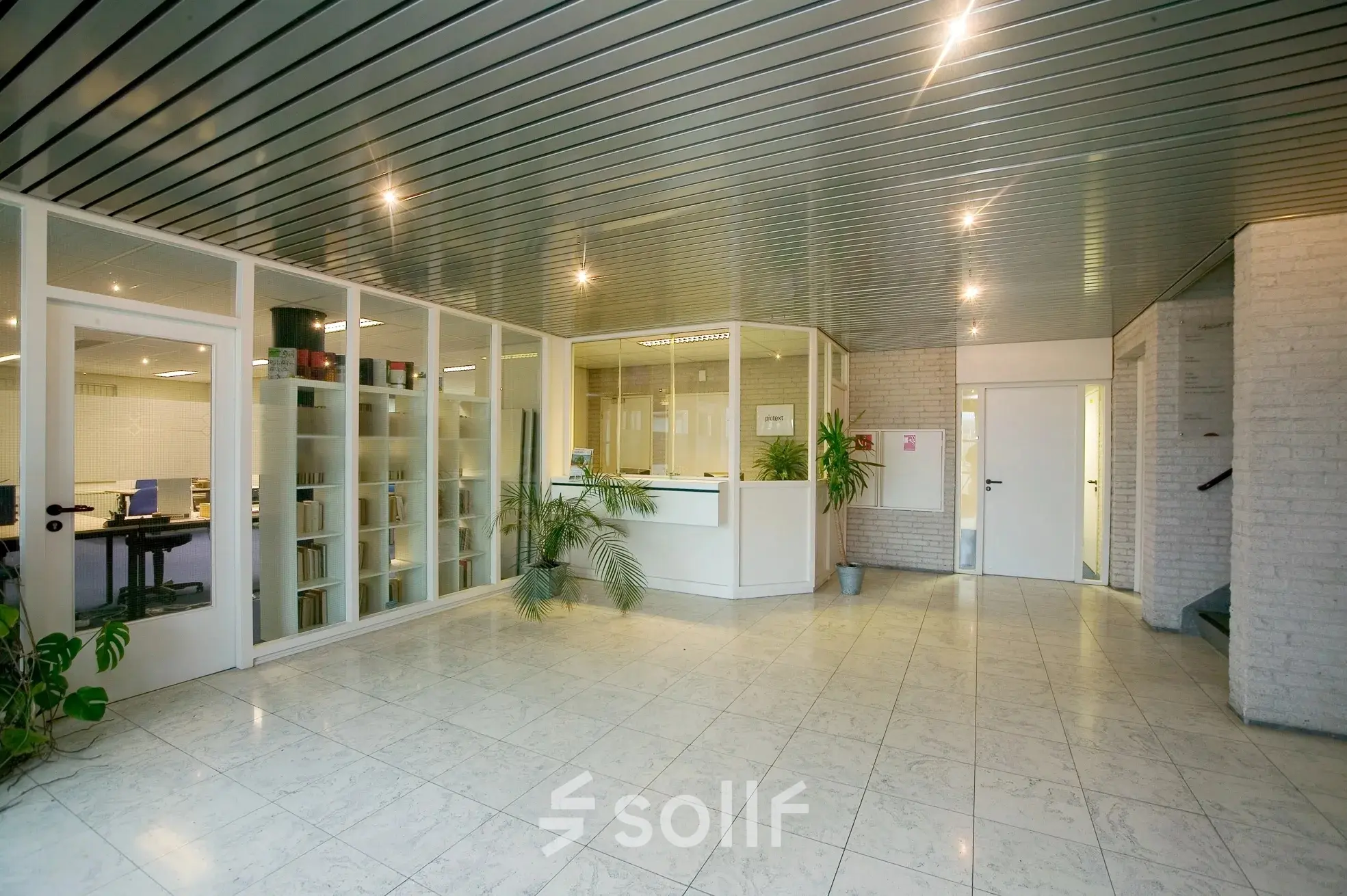 Spacious office interior at Sandtlaan 36 in Katwijk, featuring a bright reception area with bookshelves and potted plants, ideal for office space rental.
