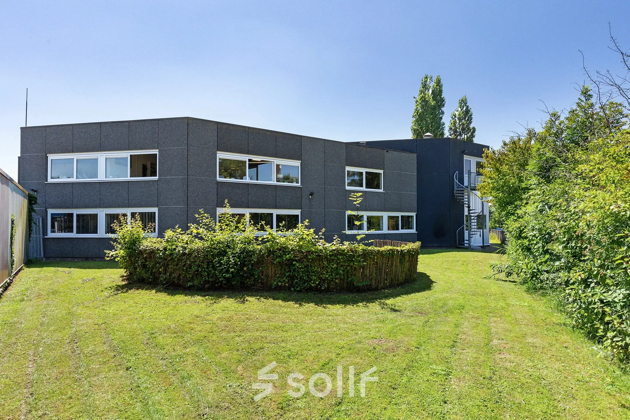 Exterior view of office building at Ouddeelstraat 7a, Leeuwarden, with lush green surroundings, available for office space rental.