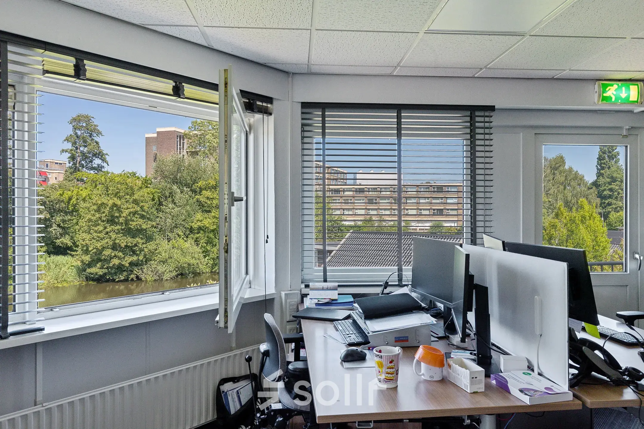 Furnished office space at Ouddeelstraat 7a, Leeuwarden, featuring desks, computers, and a view through large windows. Ideal for office space rental.
