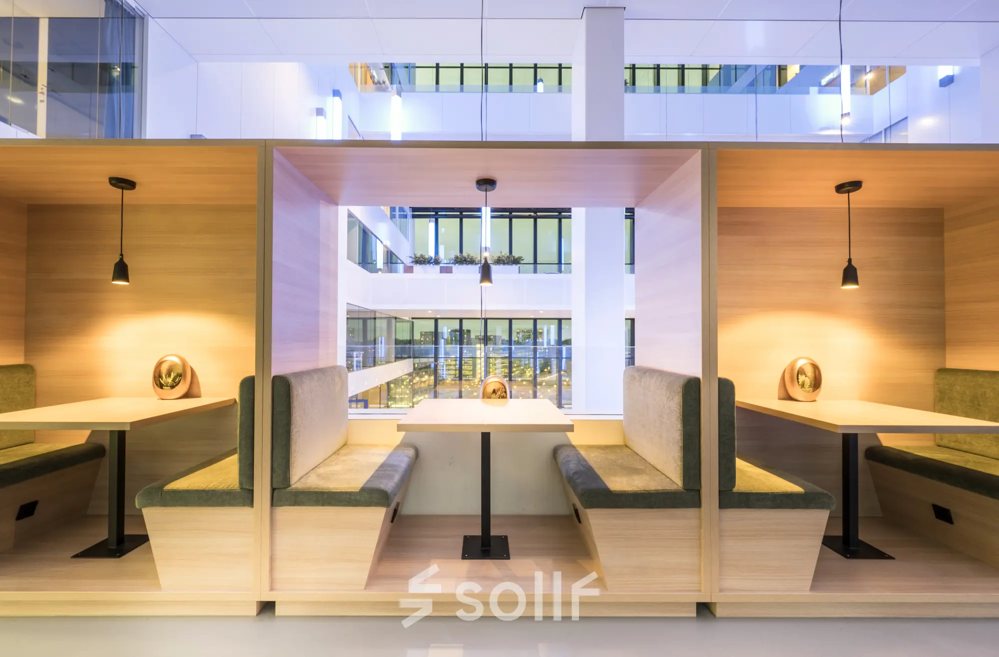Modern office space with wooden booths for rent at Bargelaan 200, Leiden, featuring ambient lighting and glass wall views.