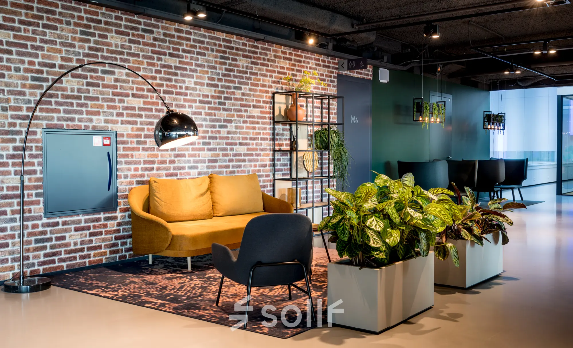 Stylish office lounge at Bargelaan 200, Leiden, featuring a modern sofa, chairs, and vibrant indoor plants, available for office space rental.