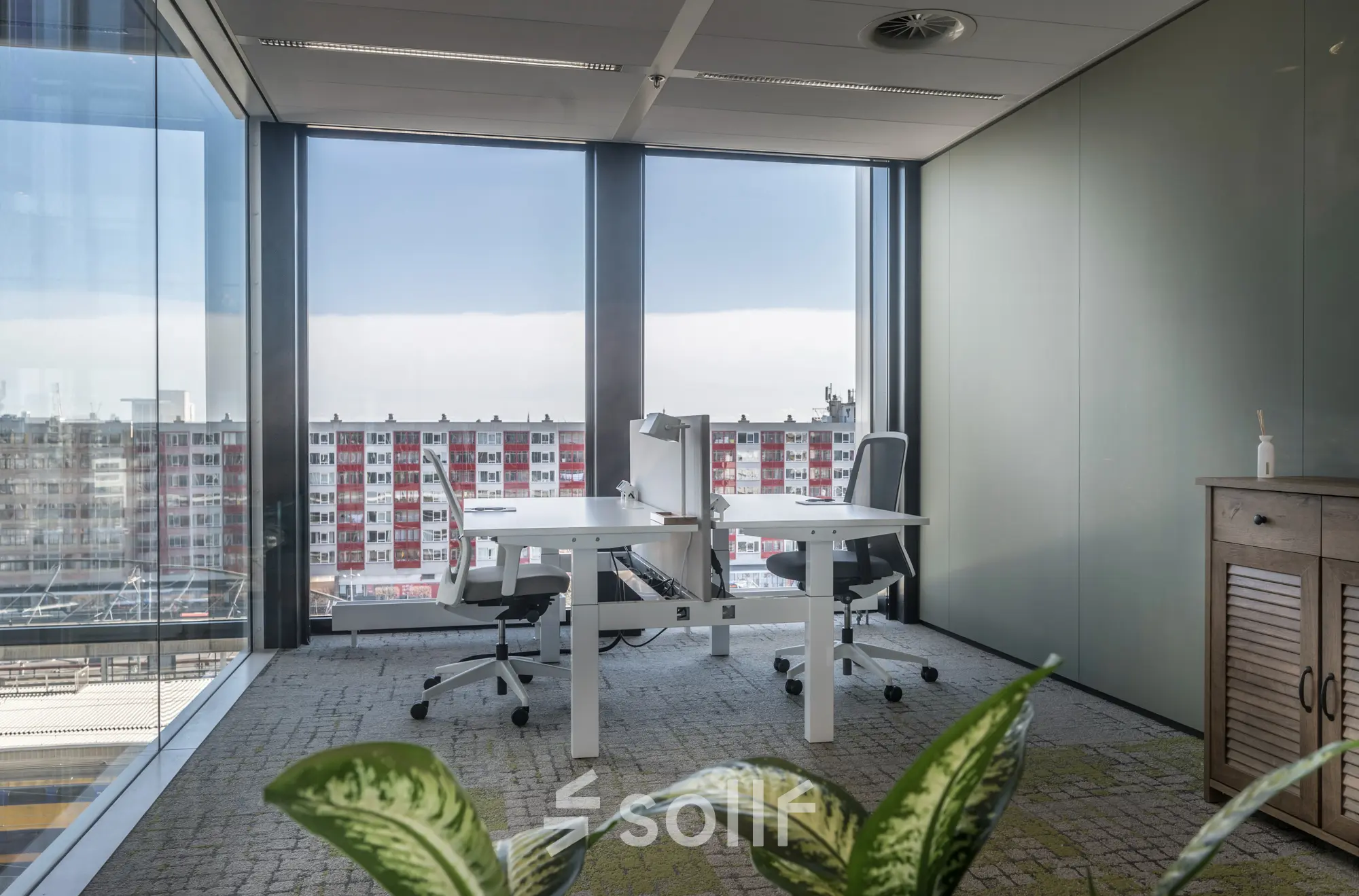 Modern office space rental at Bargelaan 200, Leiden, featuring large windows and two desks with chairs, overlooking the cityscape.