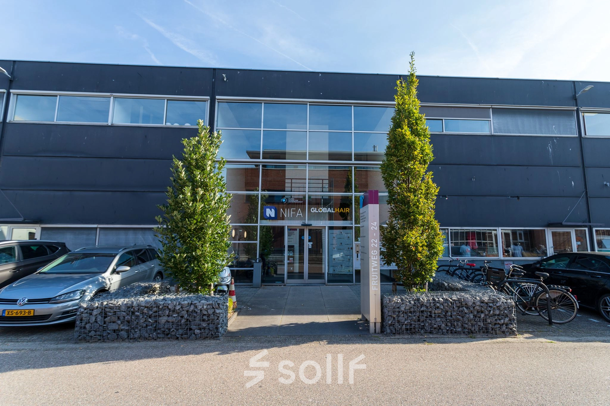 Exterior view of office space rental at Fruitweg 22, Leiden, featuring a modern facade with ample parking and bicycle racks.