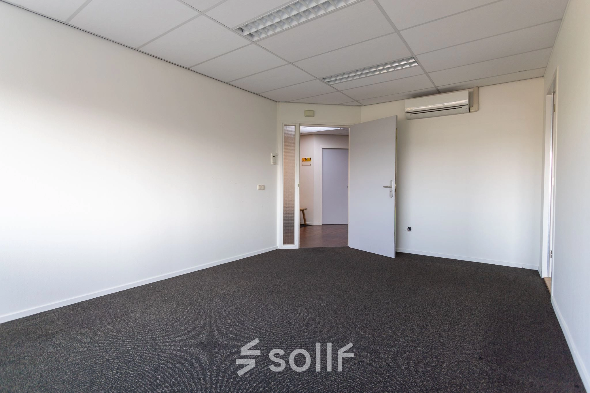 Empty office space at Fruitweg 22, Leiden, ideal for rent. Neutral walls and carpet offer a versatile area for office space rental.