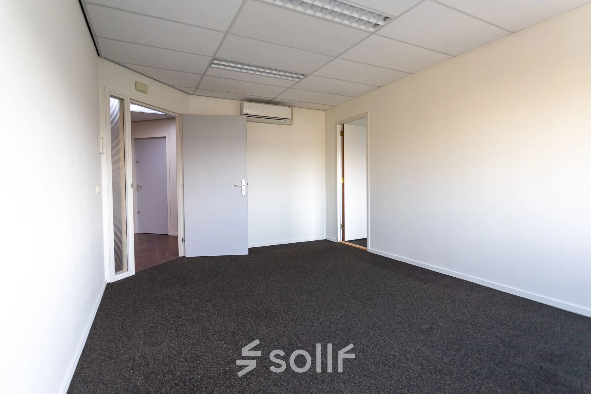 Interior view of unfurnished office space available for rent at Fruitweg 22, Leiden, featuring a carpeted floor and overhead lighting.