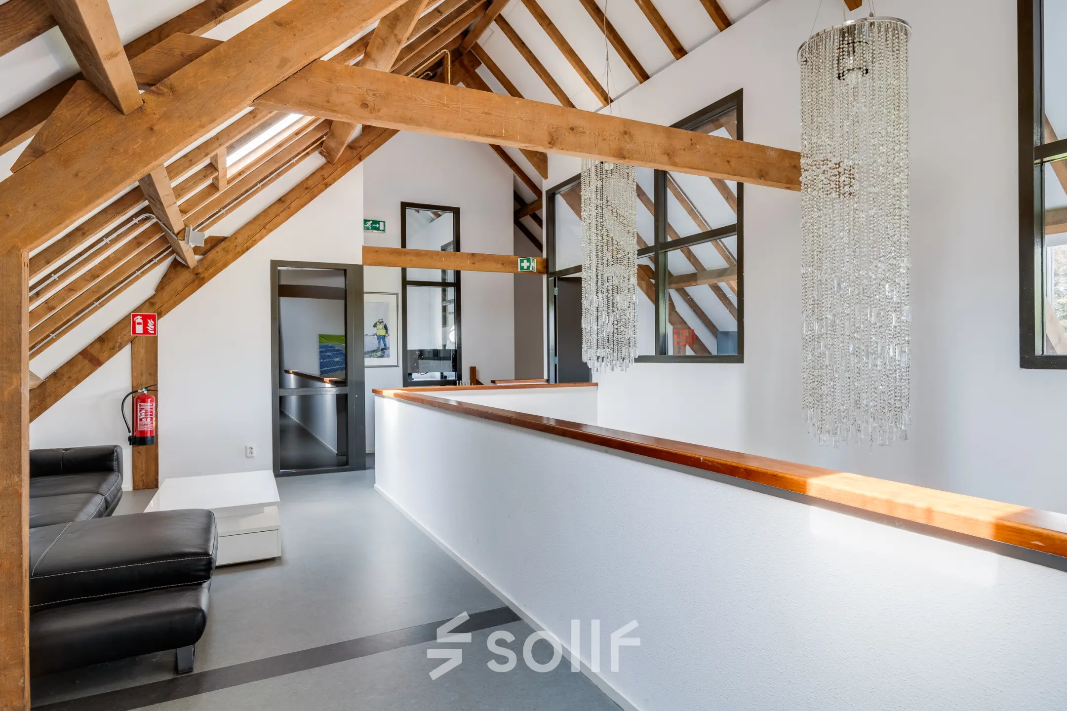 Interior of an office at Hamersveldseweg 120, Leusden, featuring wooden beams, modern furnishings, and decorative lighting. A sleek corridor connects different areas, ideal for office space rental.