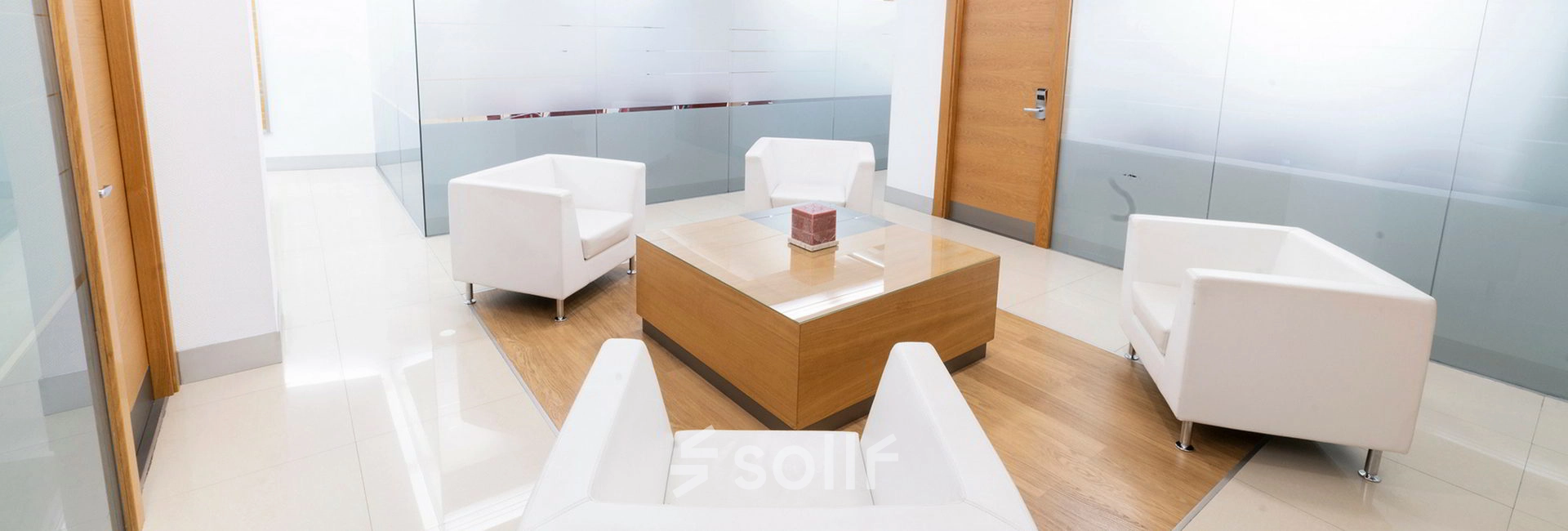 Modern office lounge at Calle de la Caléndula 93, Madrid Alcobendas, featuring sleek white chairs and a wooden table. Ideal office to rent for meetings or casual discussions.