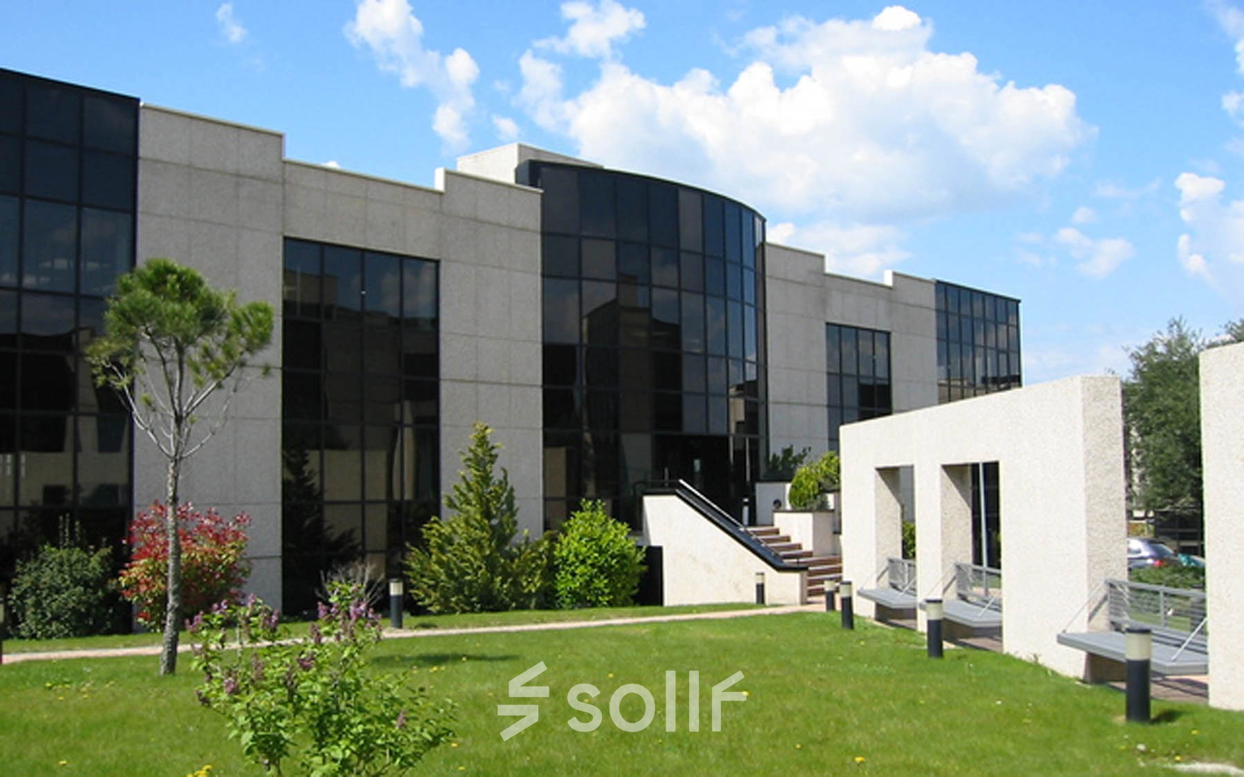 Exterior view of office building at Calle de la Caléndula 95, Madrid Alcobendas, with large windows and a garden. Ideal location for office space rental.