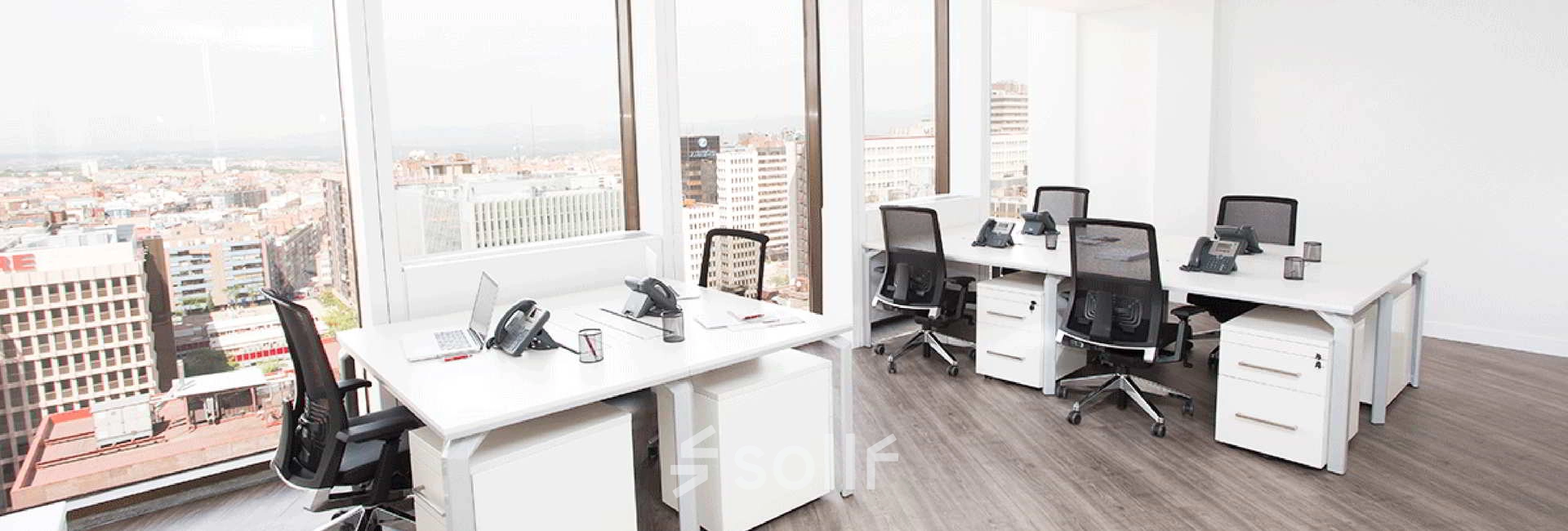 Bright office space at Paseo de la Castellana 141, Madrid Azca, featuring modern desks and chairs with a city view ideal for office space rental.