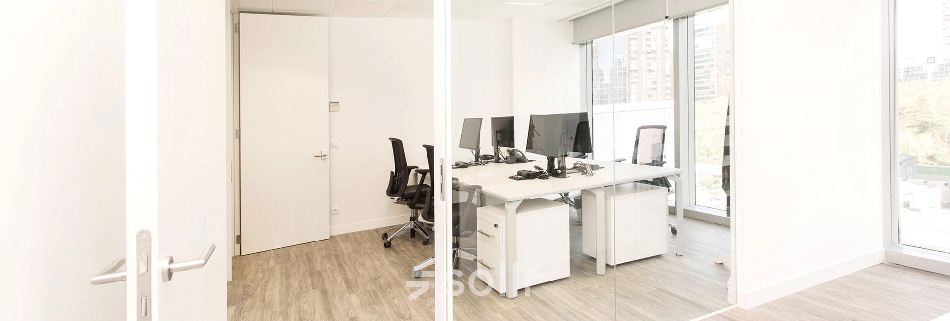 Bright office space with glass walls, featuring several desks and chairs in Madrid Azca.