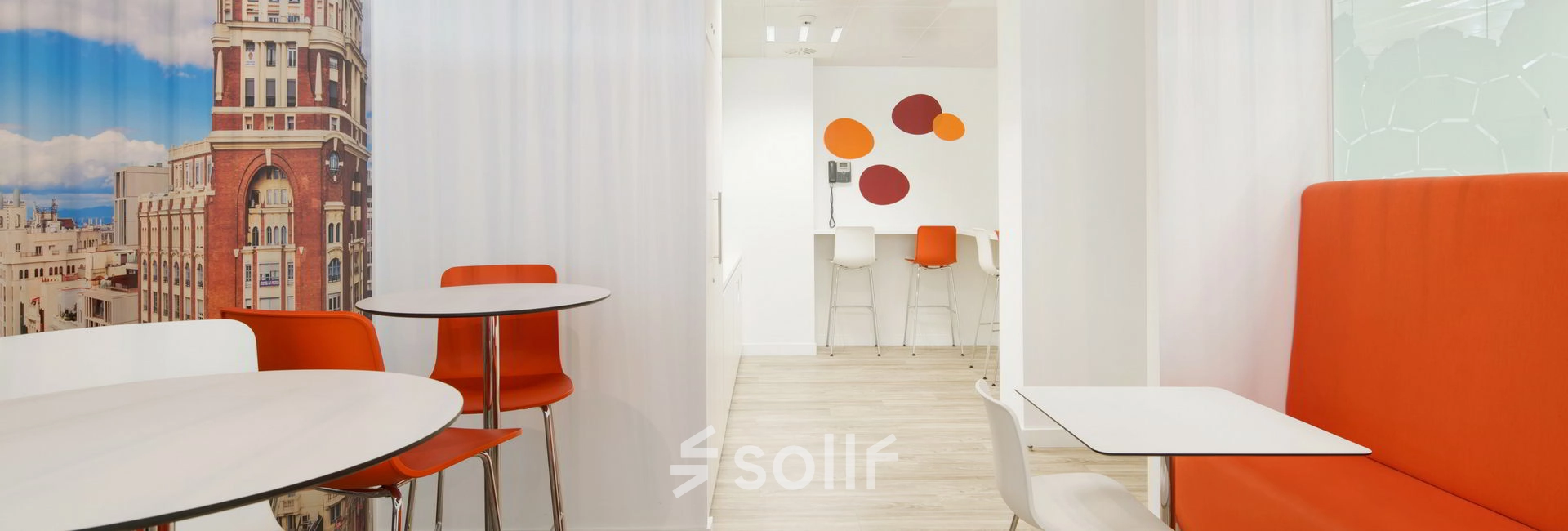 Bright, furnished office space at Paseo de la Castellana 79 in Madrid Azca with colorful seating and wall decor, ideal for office space rental.