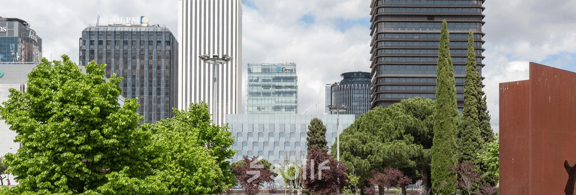 View of the skyline near Paseo de la Castellana 79 in Madrid Azca, featuring modern office buildings and greenery.