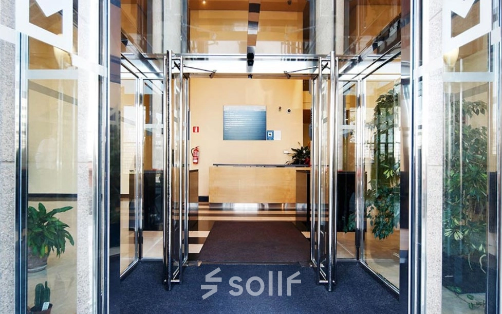 Entrance to a modern office space rental at Avenida de Aragón 334, Madrid Barajas, featuring glass doors and a reception desk.