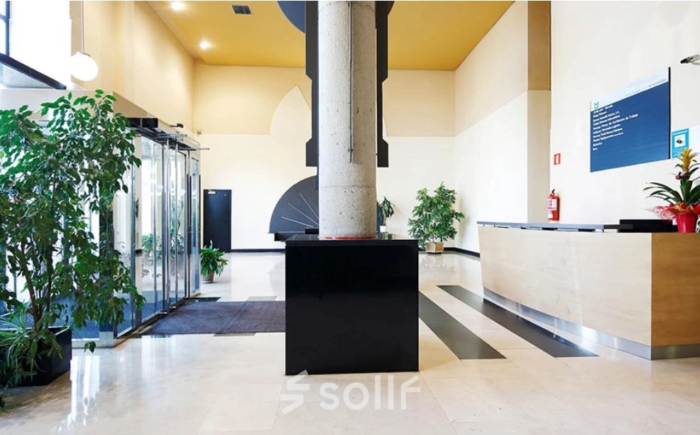 Spacious office entrance at Avenida de Aragón 334, Madrid Barajas, featuring a sleek reception desk and lush plants, ideal for office space rental.