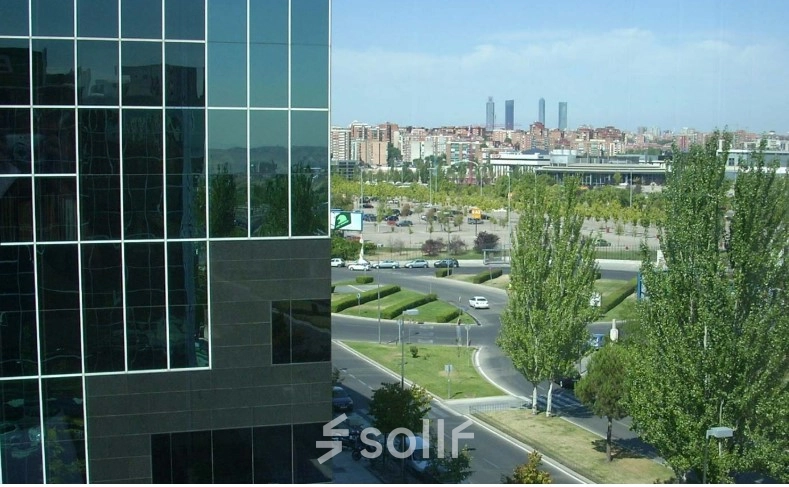 View of the modern office building's exterior with surrounding cityscape at Avenida del Partenón 16-18, ideal for office space rental in Madrid Barajas.