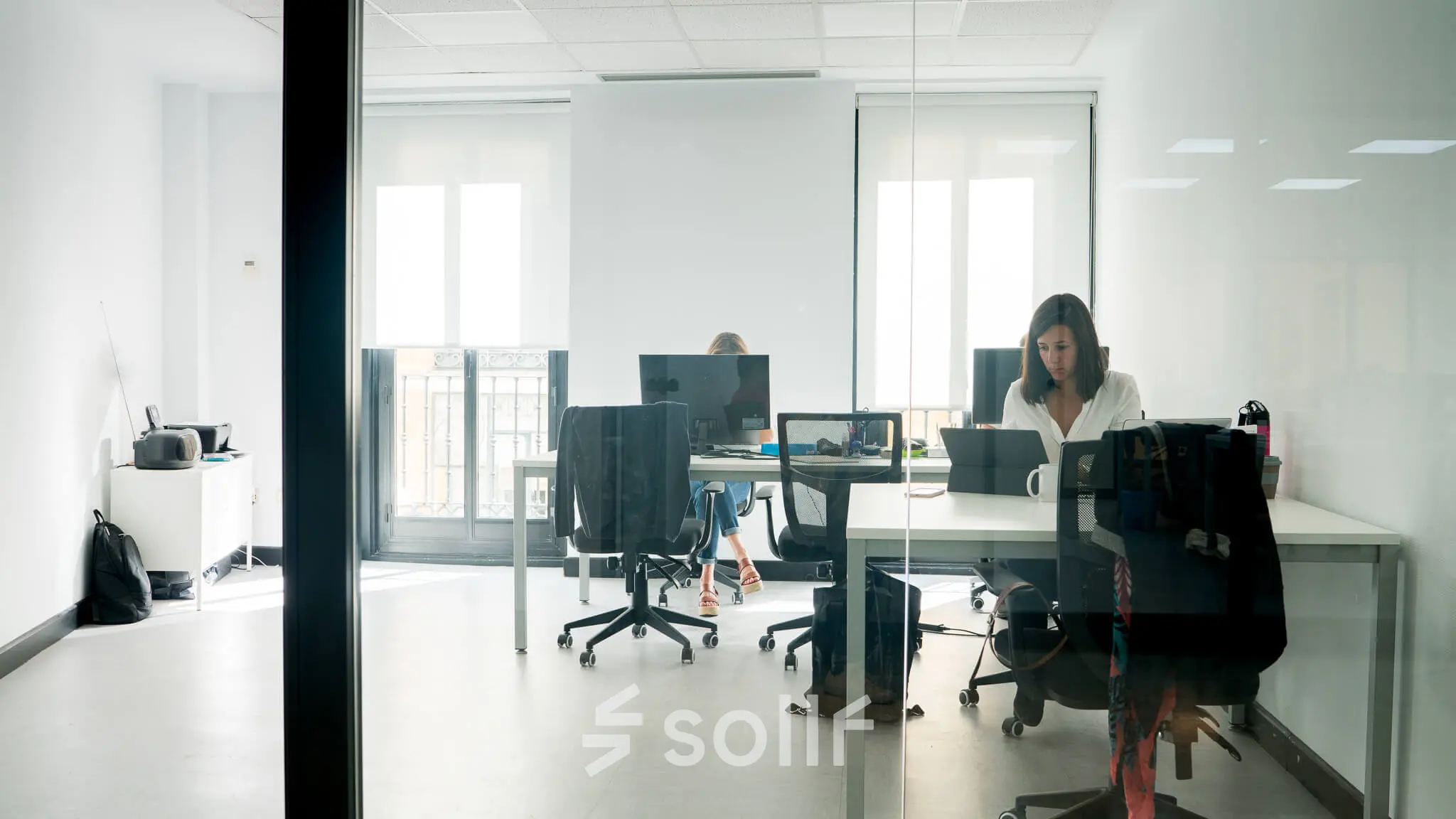 Office space rental at calle de las Huertas 11 in Madrid Center featuring professionals engaged in work activities in a bright, furnished environment.