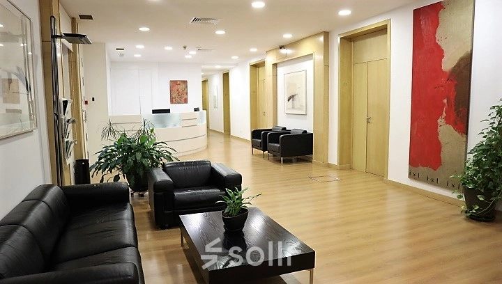 Spacious office interior with modern furniture, located on Calle Gran Vía 6, Madrid Center, perfect for office space rental. Comfortable seating and contemporary art create an inviting atmosphere for business activities.