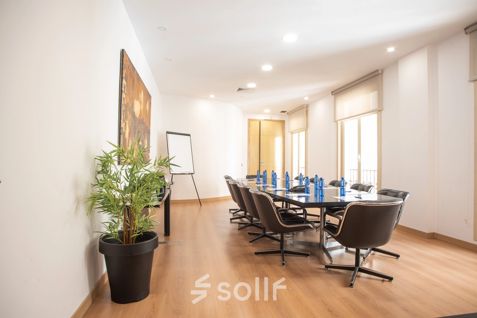 Bright office space rental at Calle Gran Vía 6, Madrid Center featuring a furnished meeting room with a long table, chairs, and a flip chart.