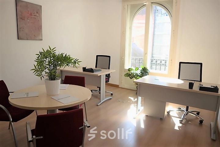 Bright office space for rent in Madrid Center on Calle Gran Vía 6, featuring desks, chairs, and natural light from large windows.