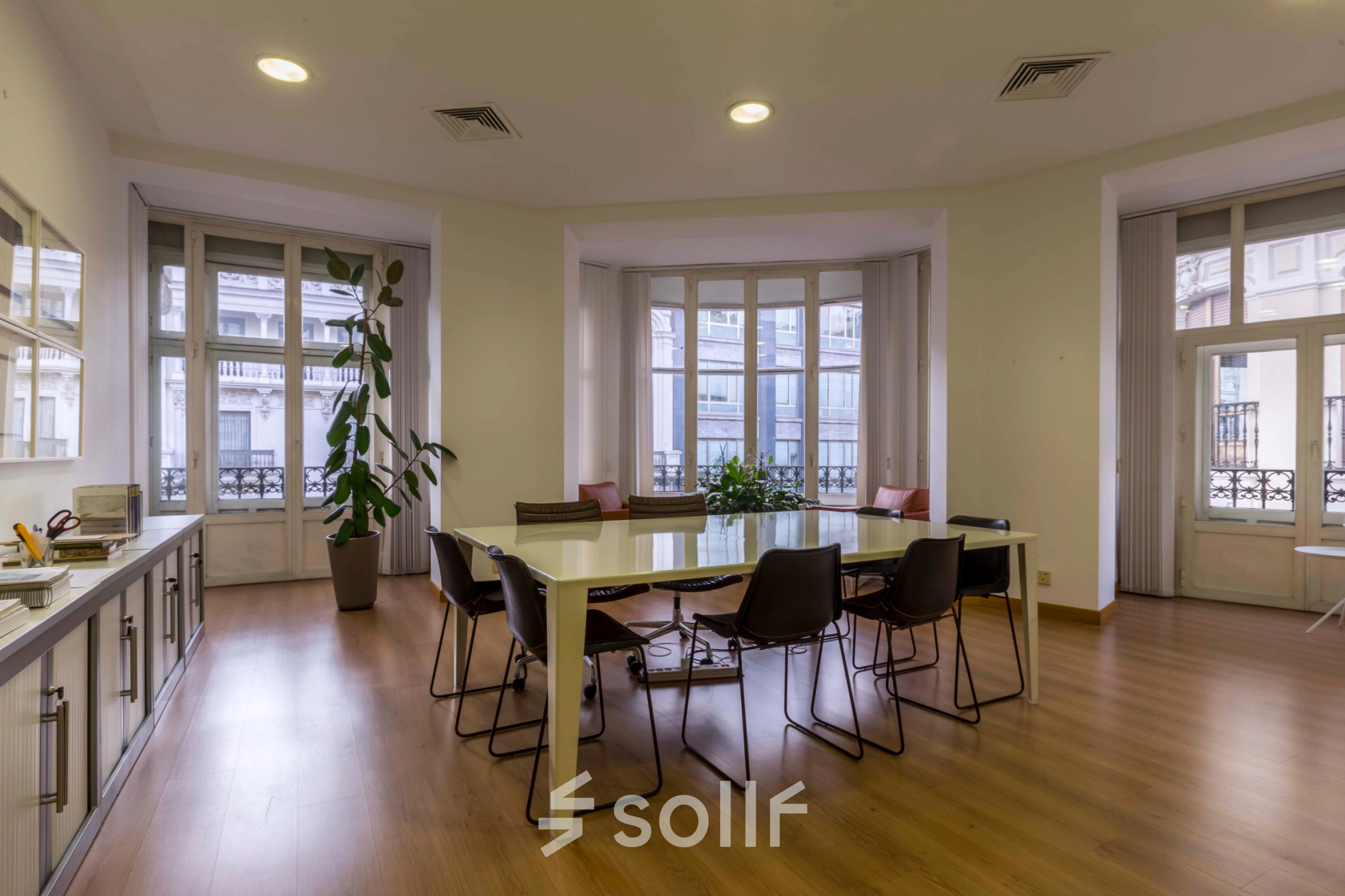 Spacious office to rent at Calle Gran Vía 6 in Madrid Center, featuring a modern meeting area with large windows, table, and chairs suitable for office space rental.