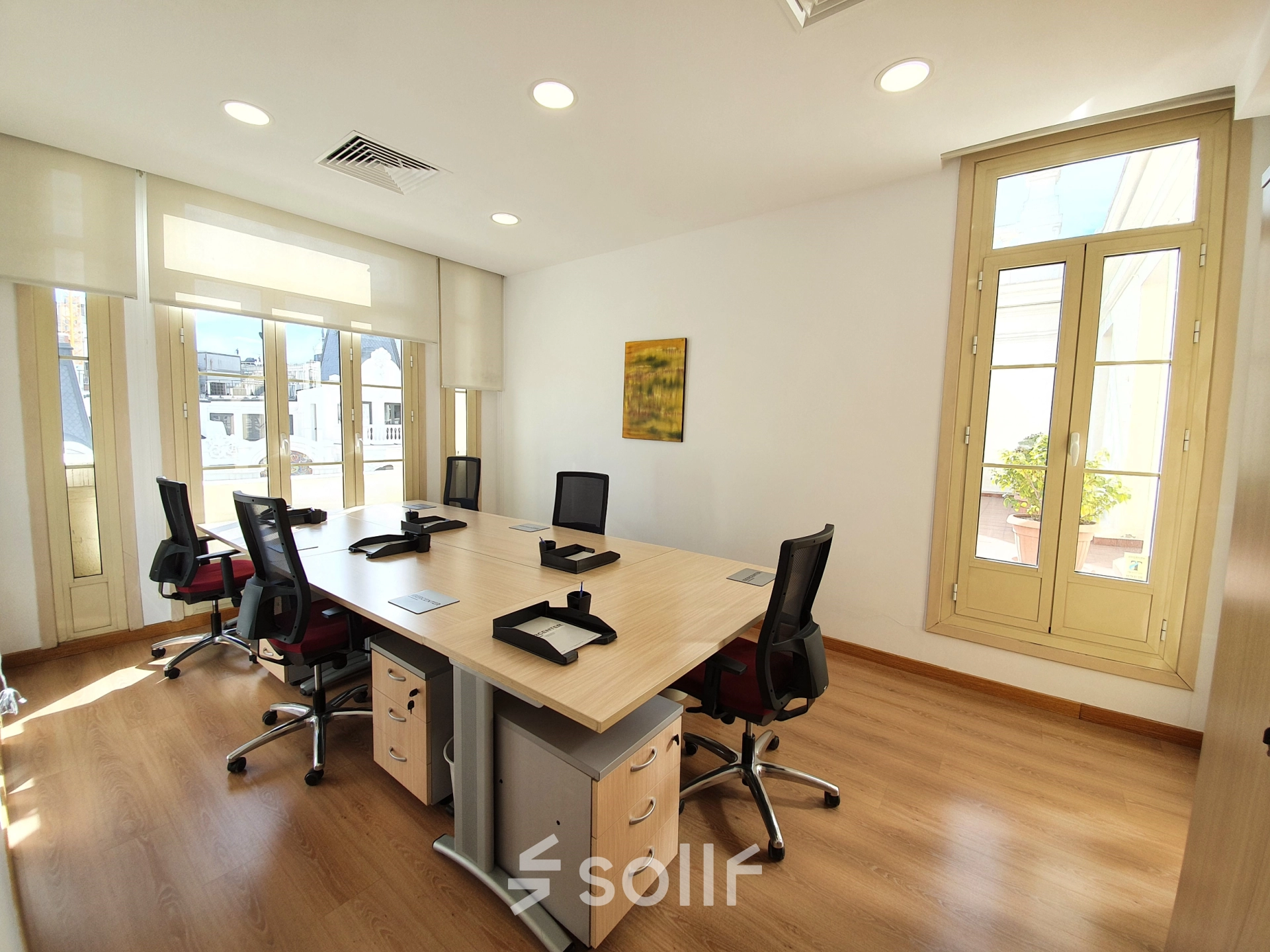 Bright office space for rent at Calle Gran Vía 6, Madrid Center, featuring large windows, desks, and chairs, perfect for office space rental.