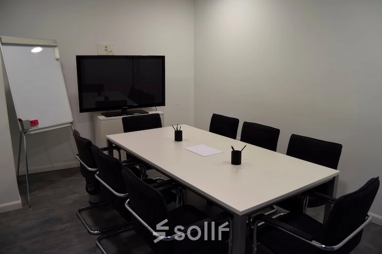 Modern conference room for office space rental at Plaza Santa María Soledad Torres Acosta 1, Madrid Center, featuring a large table, chairs, a whiteboard, and mounted screen.