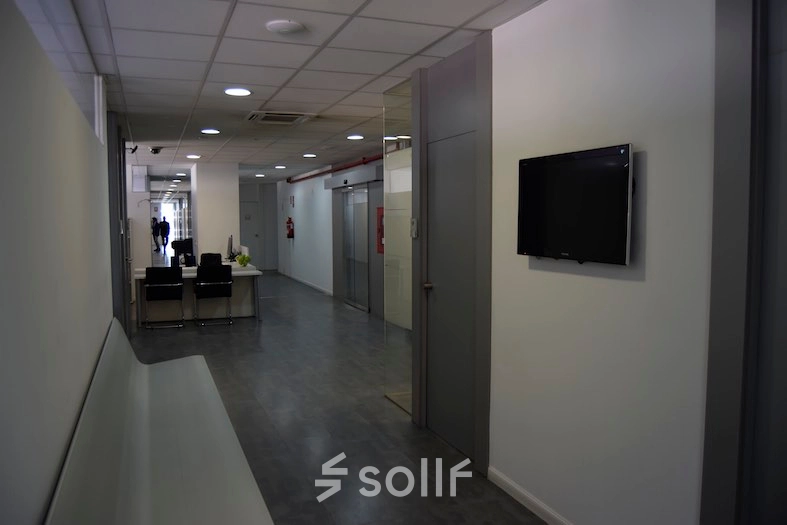 Office space in Plaza Santa María Soledad Torres Acosta 1, Madrid Center, featuring a corridor with a sleek desk, chairs, and wall-mounted TV for office space rental.