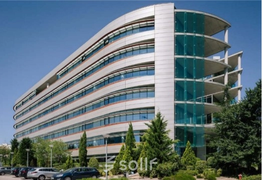 A modern office building at Calle Vía de los Poblados 1, Madrid Hortaleza, ideal for office space rental, surrounded by greenery and parking facilities.