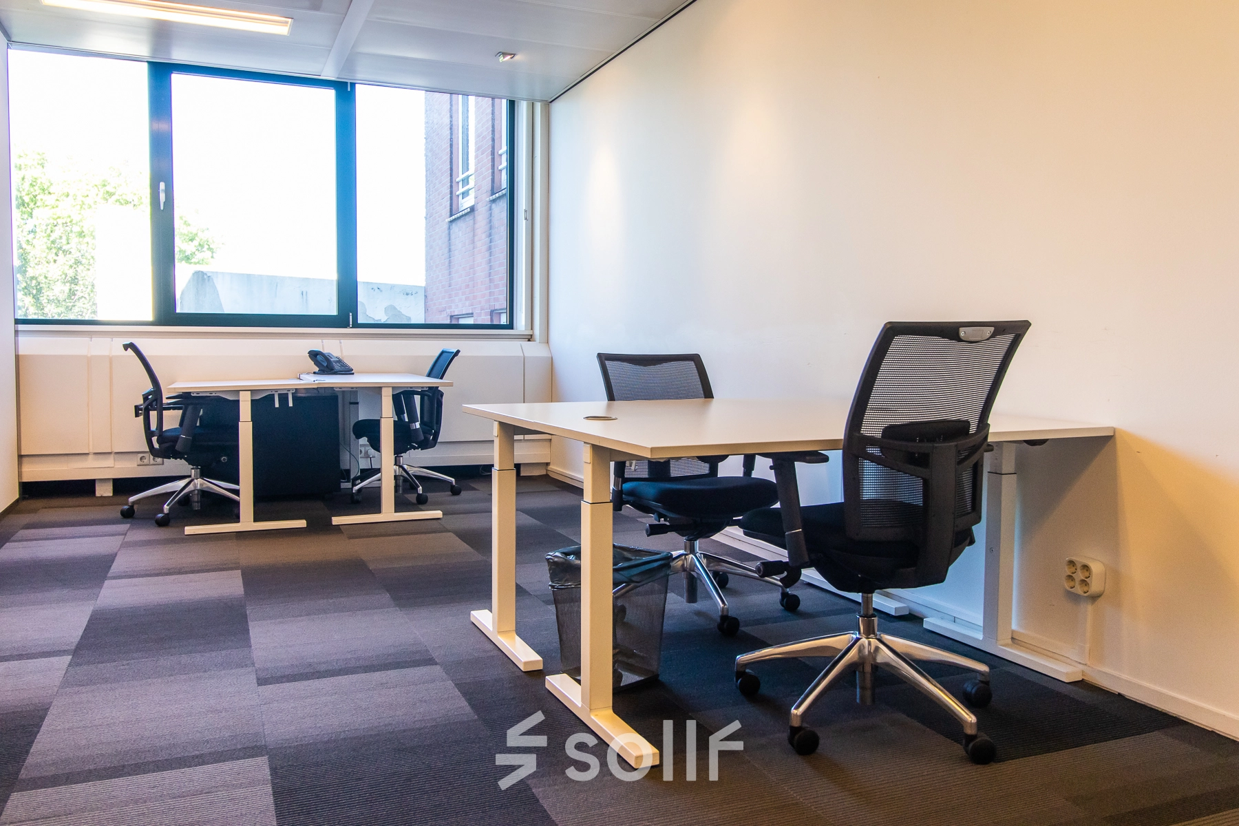 A furnished office space at Paseo de Recoletos 5, Madrid Recoletos, featuring desks and chairs, ideal for rental. The office to rent is well-lit with large windows.