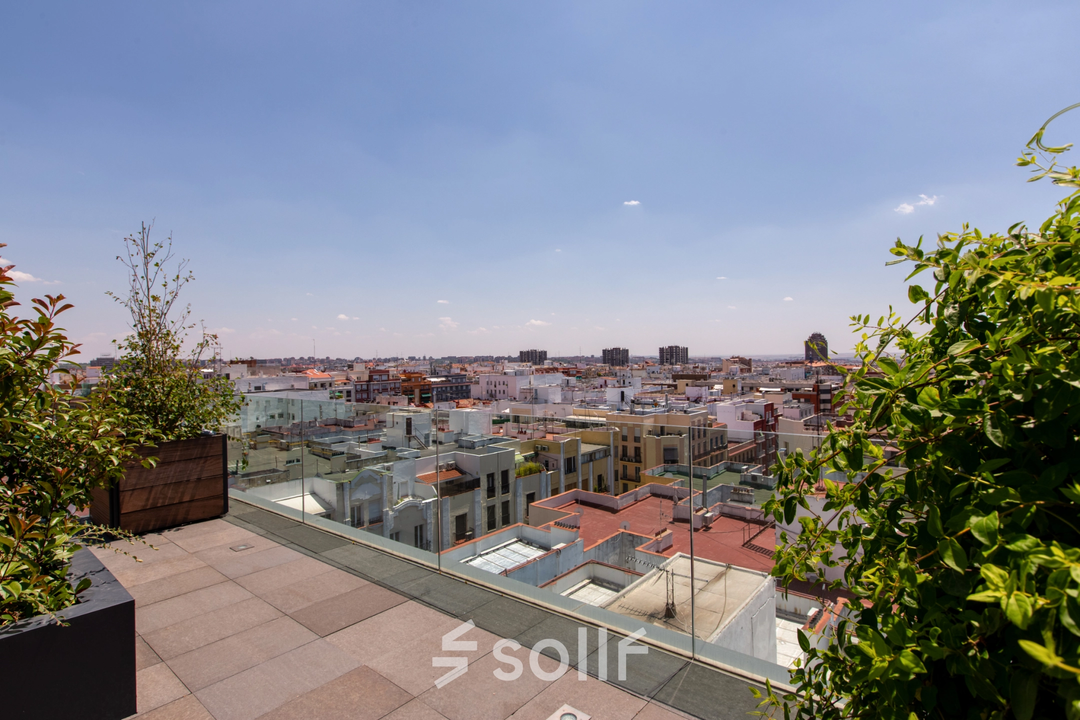 A rooftop view of Madrid with glass railings and greenery, highlighting potential for office space rental opportunities.