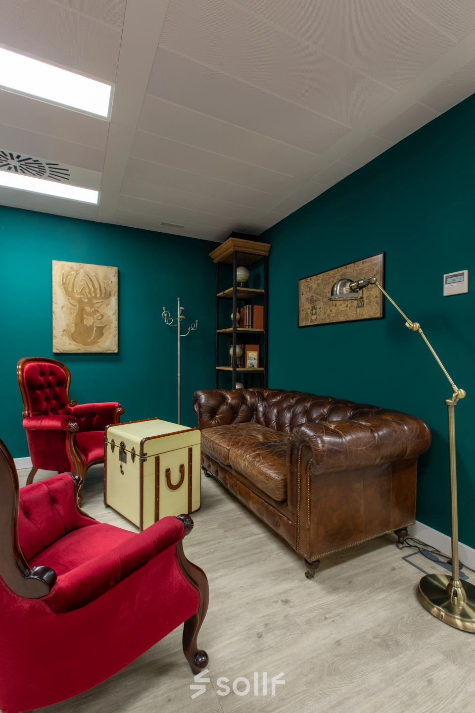 Cozy office space with vintage leather couch, red armchairs, and decor, ideal for office space rental on calle de O'Donnell, Madrid Retiro.