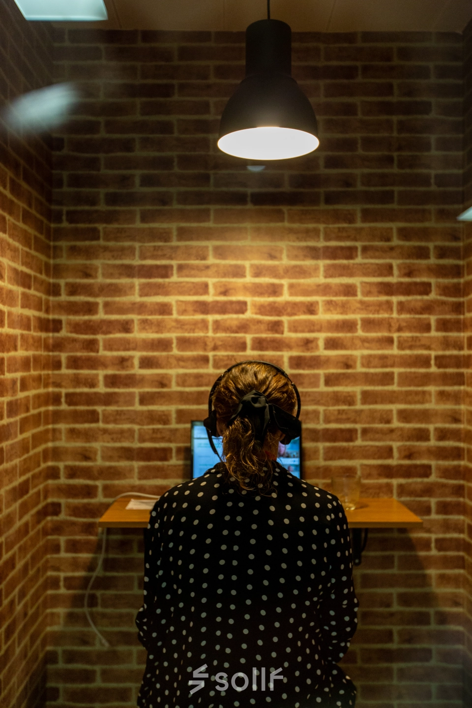 An individual working on a laptop in a brick-walled office space, ideal for those seeking office space rental at calle de O'Donnell, Madrid Retiro.
